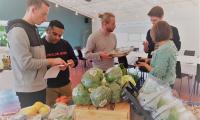 Billede fra den madlavningsworkshop, der blev gennemført på ungeweekenden i november 2019. 5 unge står koncentrerede samlet omkring et bord fyldt med friske fødevarer og med opskrifter og køkkenredskaber i hånden. 