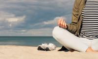 Kvinde mediterer på strand