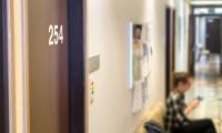 Lette sløret billede af en gang, hvor en patient venter på at komme til lægen ved en dør med et nummer på. 