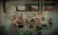 Billede viser en gruppe på unge i en svømmehal, smilende og med armene i vejret. Taget på ungeweekend november 2021. 