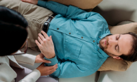 Stockphoto man ligger på ryggen, lukkede øjne, hypnotisør mærker ham på håndleddet. 