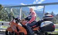 Privatfoto af Liselott Blixt, formand for Psoriasisforeningen, der sidder på sin røde motorcykel foran et bjerglandskab. 