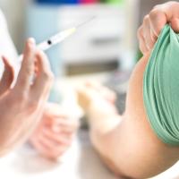 Billede er et neutralt stockphoto der viser et udsnit af en hånd der holder en nål og skal til at give en vaccination i armen på en anden person. Ingen ansigter kan ses. 