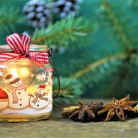 Arkivbillede juledekoration, et fyrfadslys med snemænd på og grand i baggrunden, stemningsbillede.
